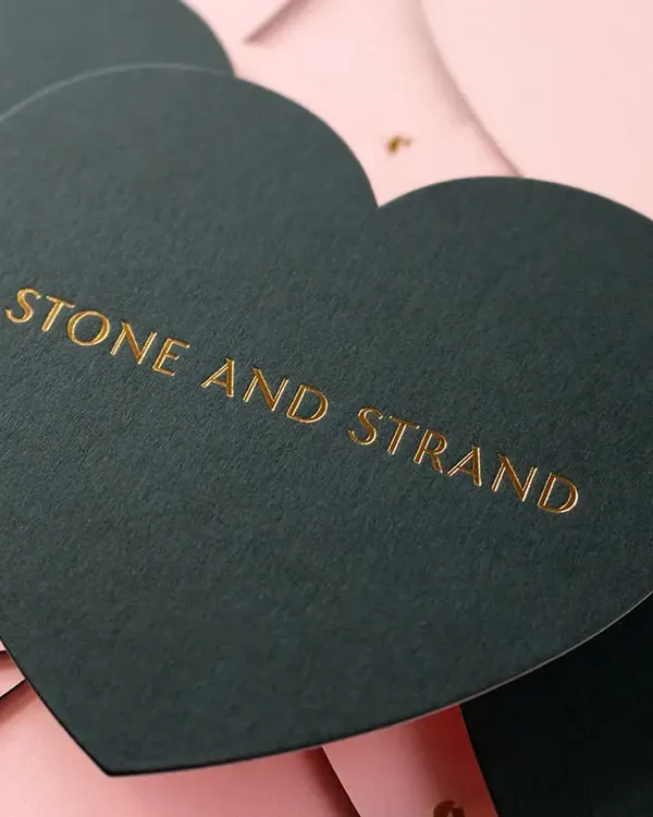 Heart-shaped die-cut note cards in dark green with gold foil Stone and Strand wordmark on pink envelopes