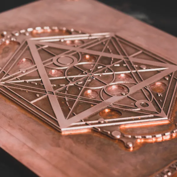 Close-up of a copper foil stamping die showing the carved triangular geometric artwork