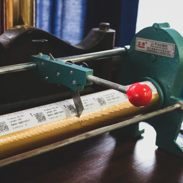 Green foil cutter trimming a roll of copper foil to size in the studio