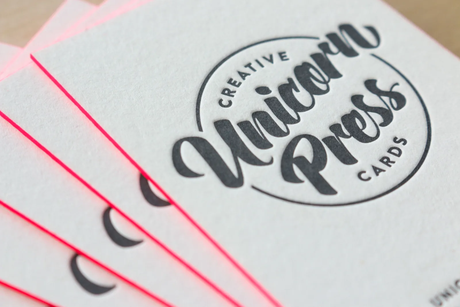 Fanned letterpress business cards with a deep impression in black ink and neon pink edge paint