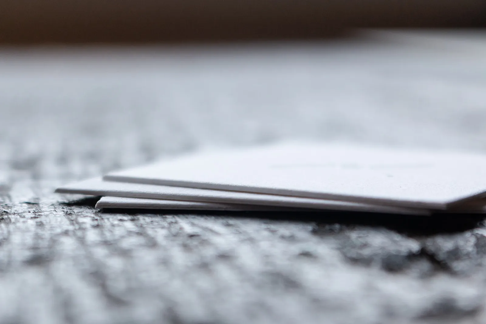 Edge profile of two square business cards showing the duplexed two-sheet construction bonded into a single 220lb double-thick card