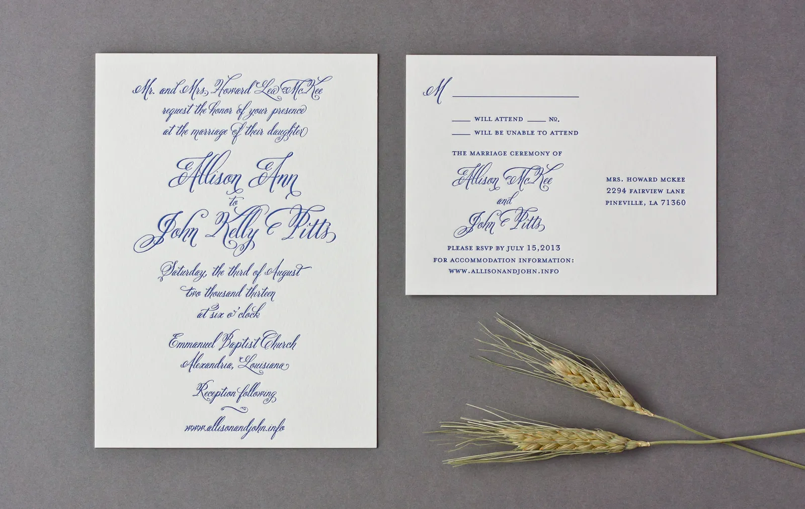 Overhead view of letterpress wedding invitation and RSVP card in cobalt blue, styled with wheat sprigs on a gray surface