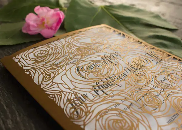 Letterpress wedding invitation with gold laser-cut floral sleeve on white cotton paper