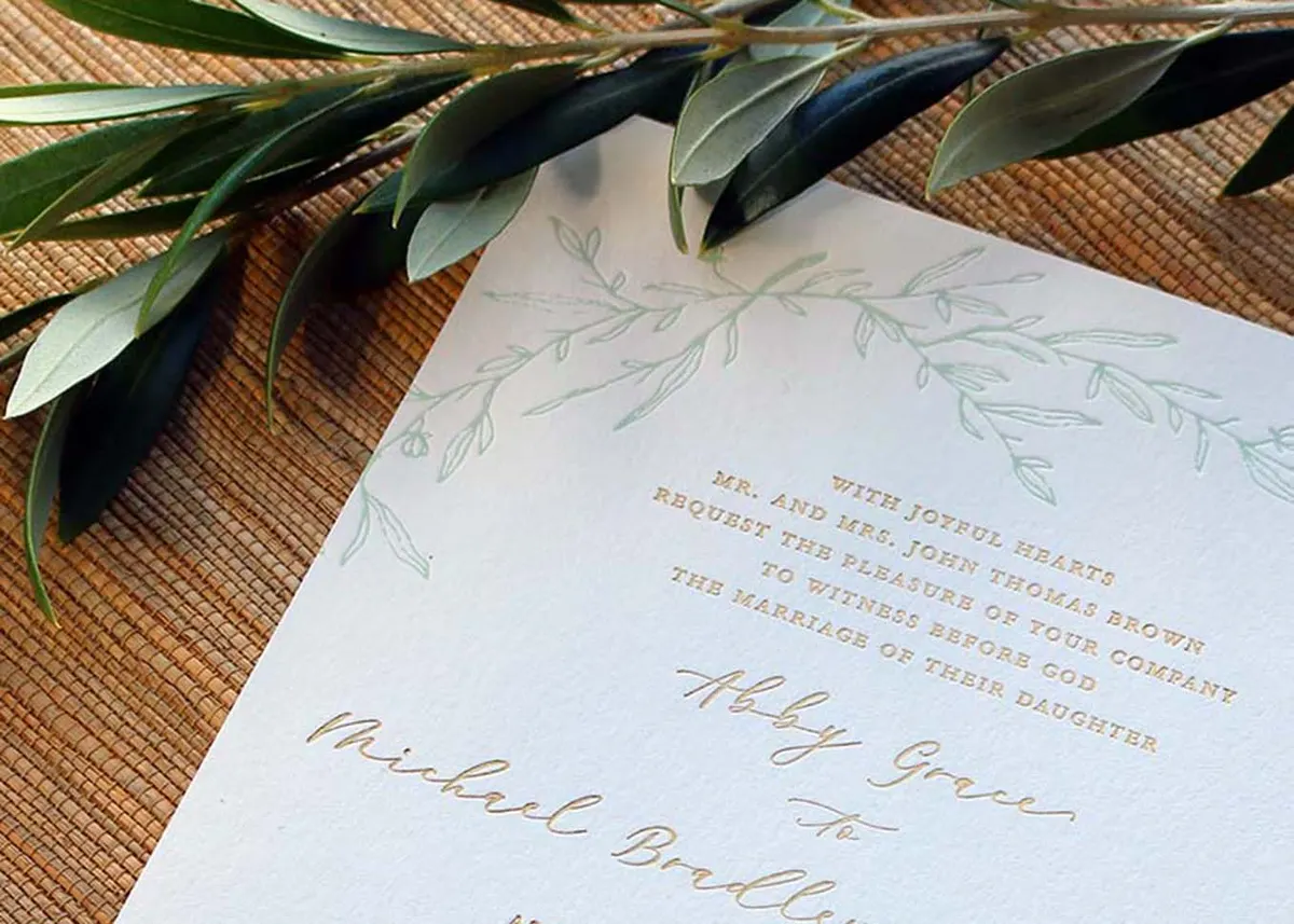 Wedding invitation displayed with coordinating sage green envelope on natural surface