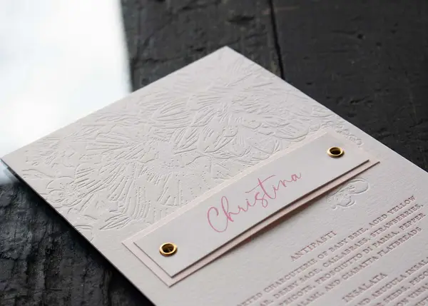 Letterpress wedding menu with blind deboss floral pattern and die-cut name tag
