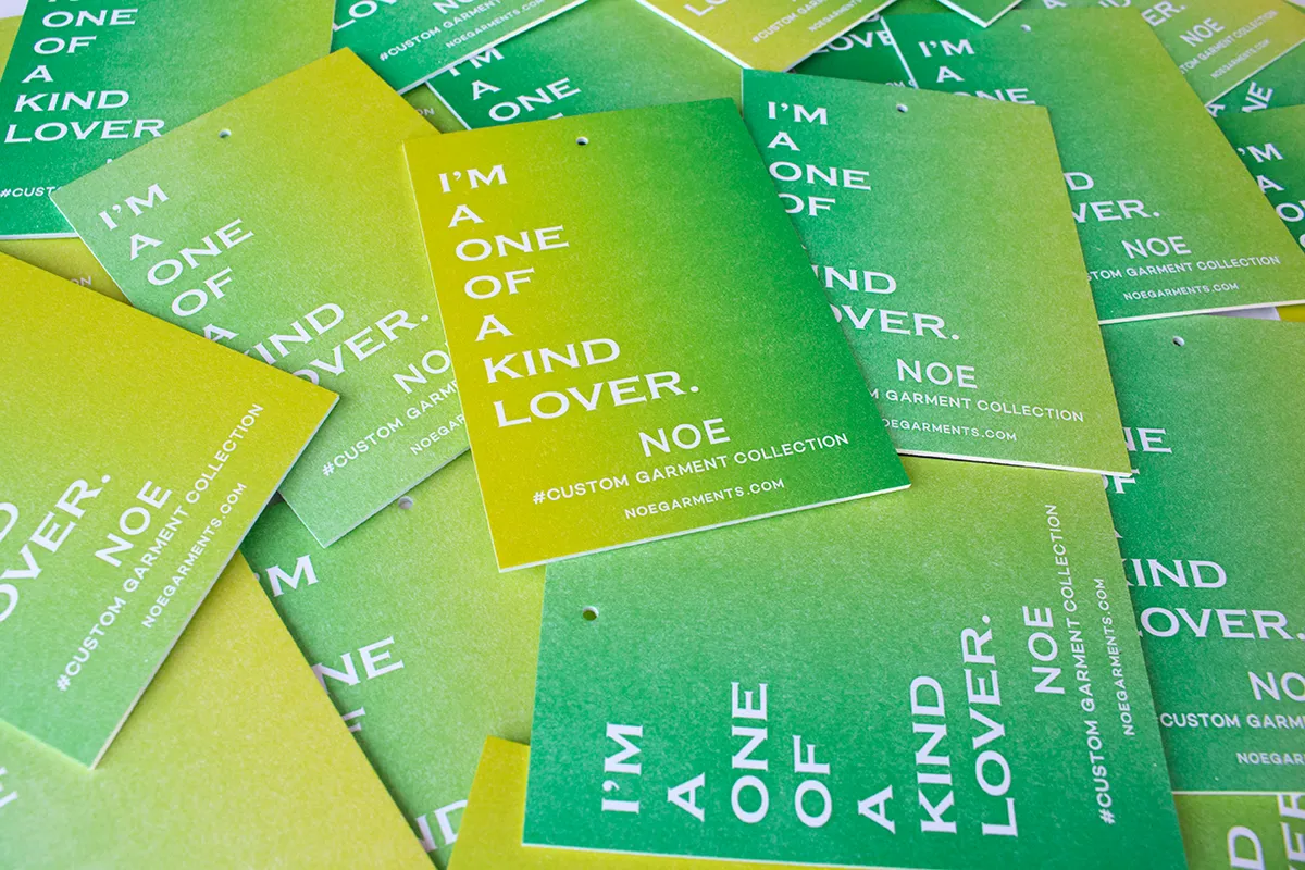 Overhead stack of green-to-yellow rainbow roll hang tags showing gradient variation across individual prints