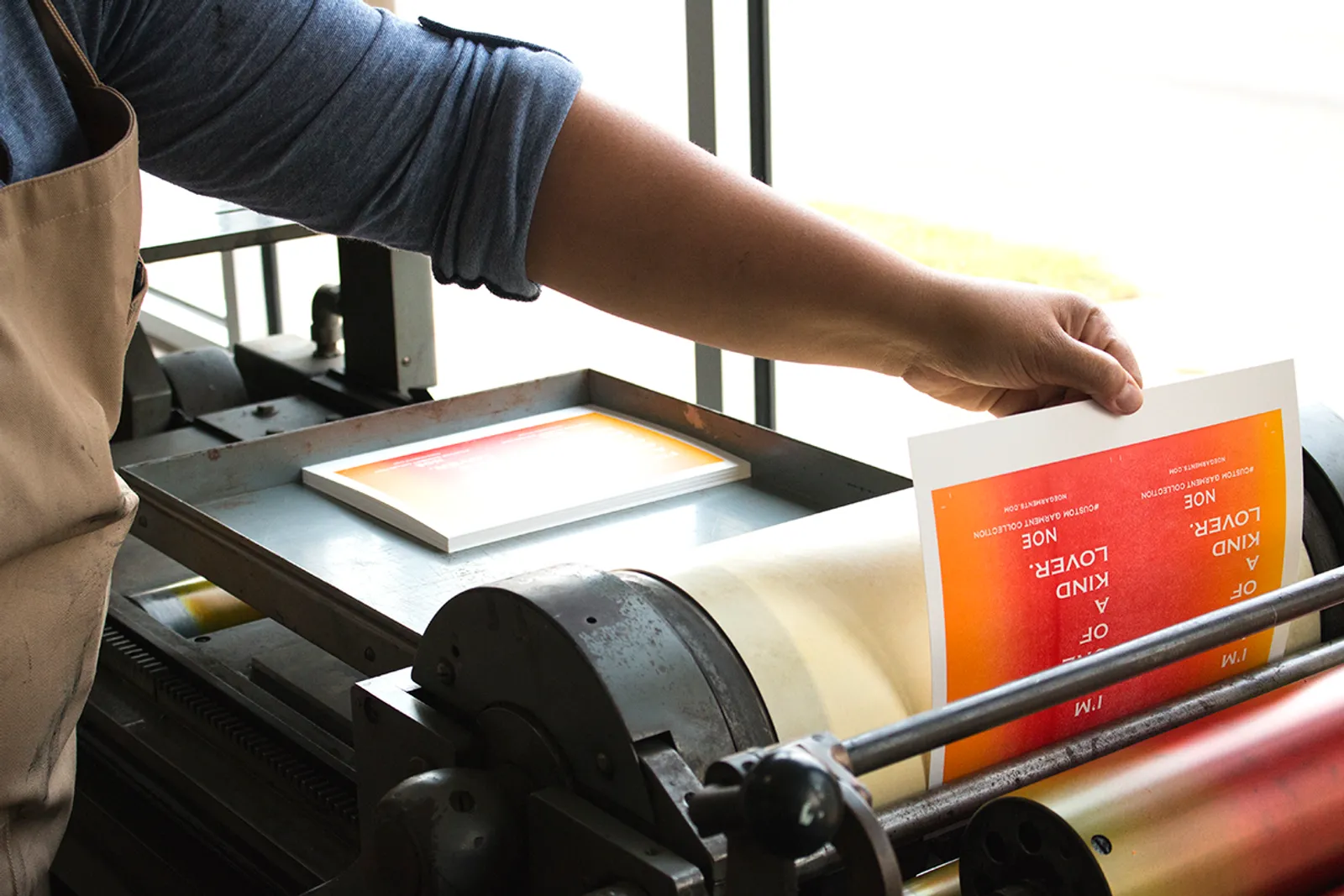 Overhead pile of rainbow roll letterpress hang tags in red, orange, green, blue, and pink gradients scattered together